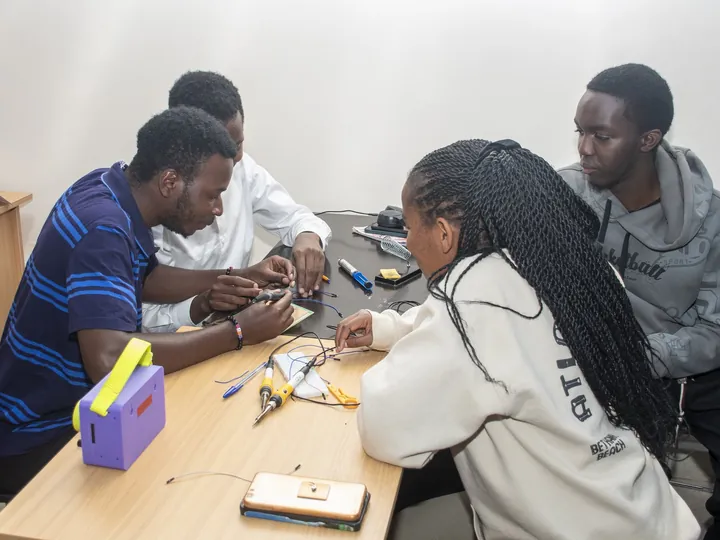 Students at a bench soldering and wiring a circuit next to their EMA Power Box